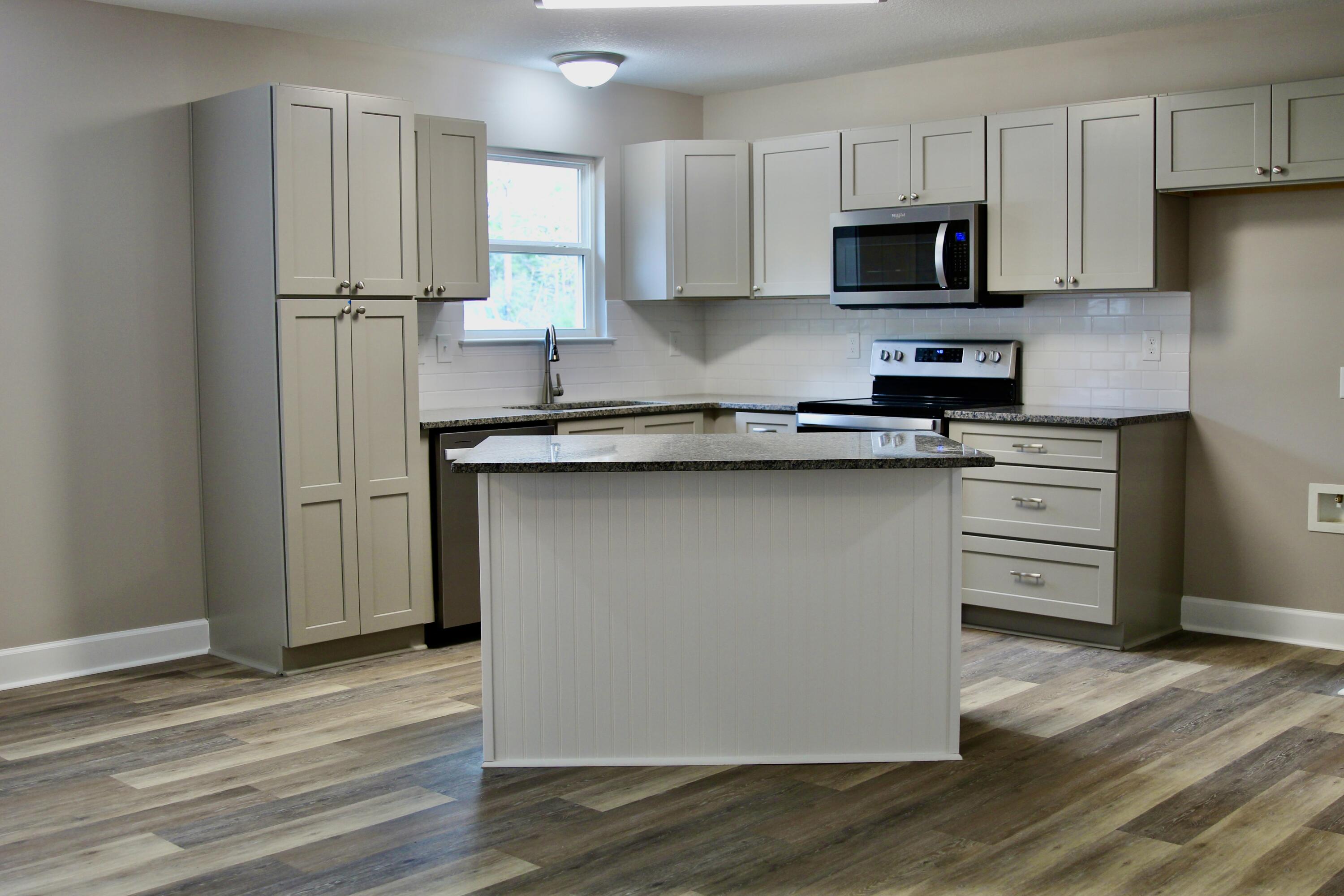 4639 Falcon Way Crestview, FL 32539 - Photo 12 of 40 a kitchen with stainless steel appliances granite countertop a stove a refrigerator a sink a microwave oven with wooden floor and cabinets