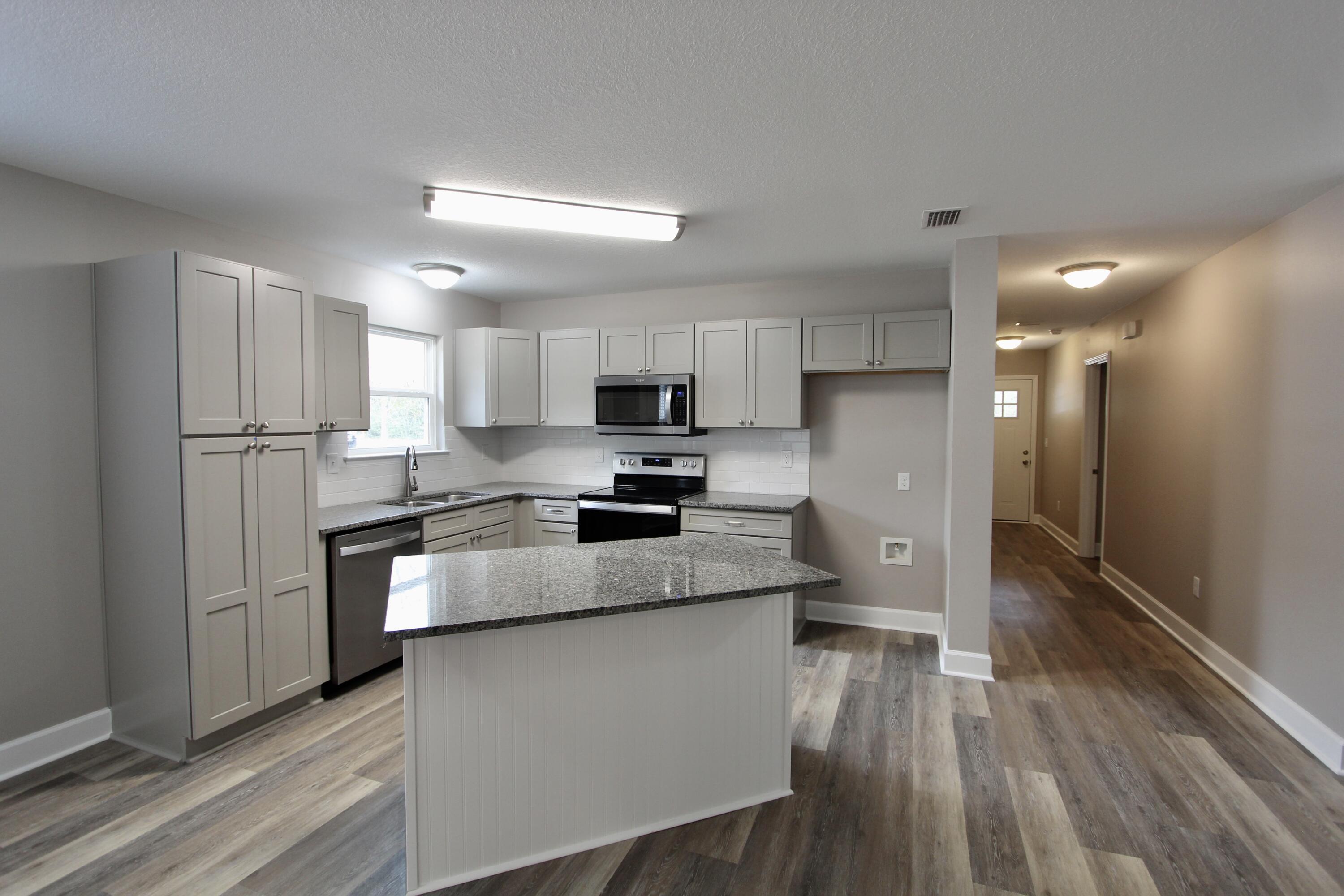 4639 Falcon Way Crestview, FL 32539 - Photo 19 of 40 a kitchen with stainless steel appliances granite countertop a refrigerator a sink dishwasher a stove top oven a refrigerator and white cabinets with wooden floor