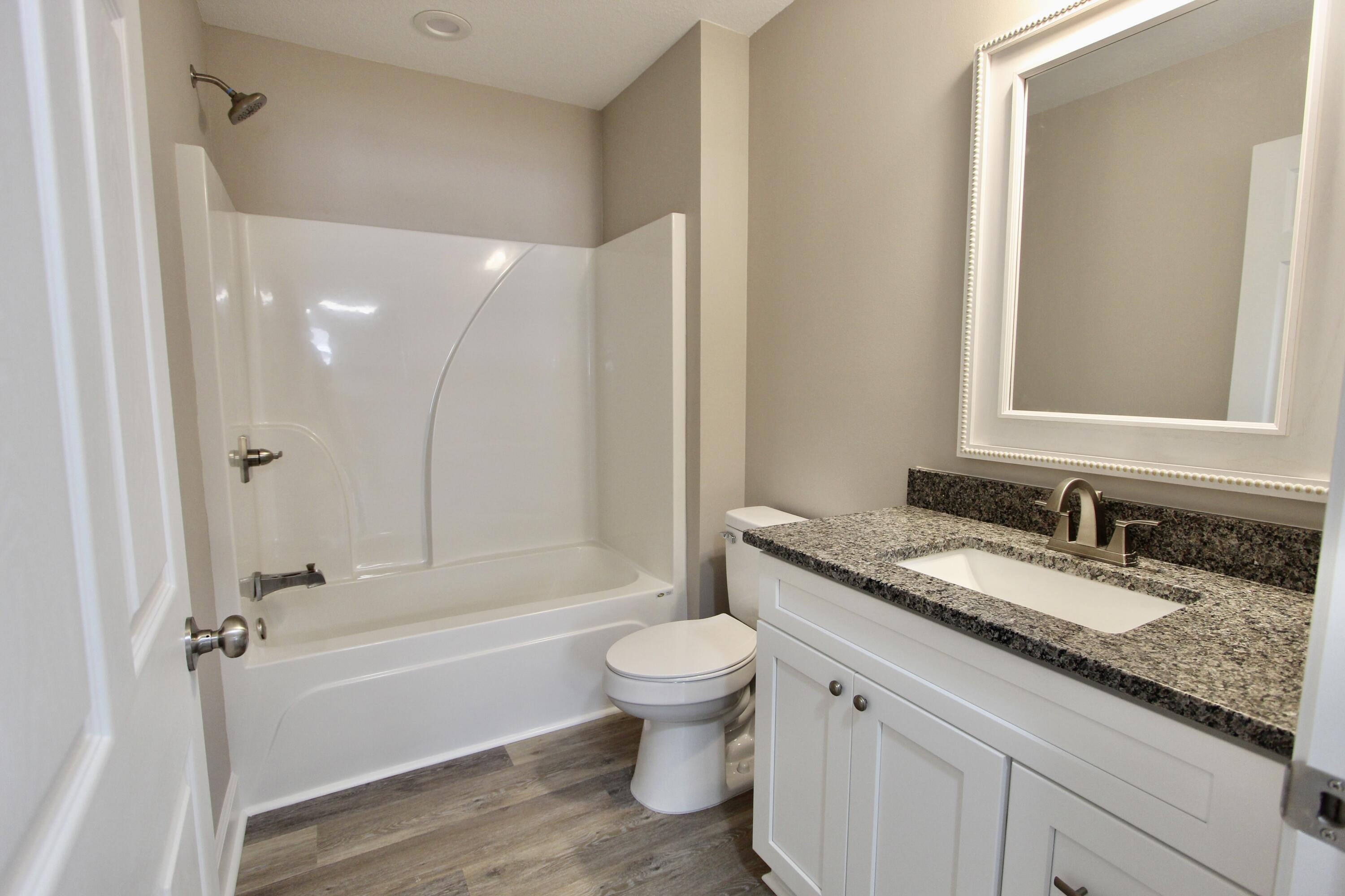 4639 Falcon Way Crestview, FL 32539 - Photo 27 of 40 a bathroom with a granite countertop sink a toilet and a large mirror