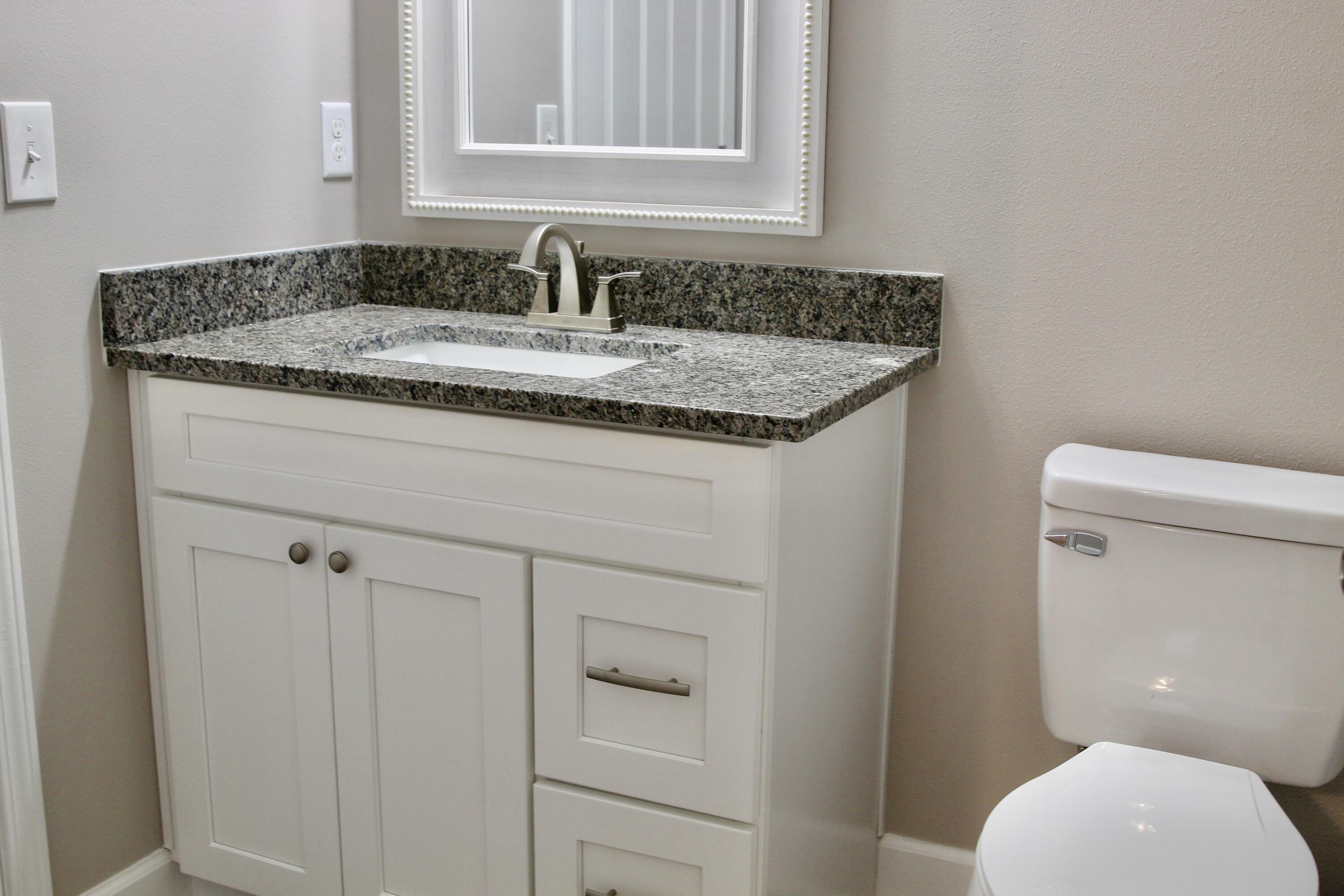 4639 Falcon Way Crestview, FL 32539 - Photo 32 of 40 a bathroom with a granite countertop toilet sink and mirror