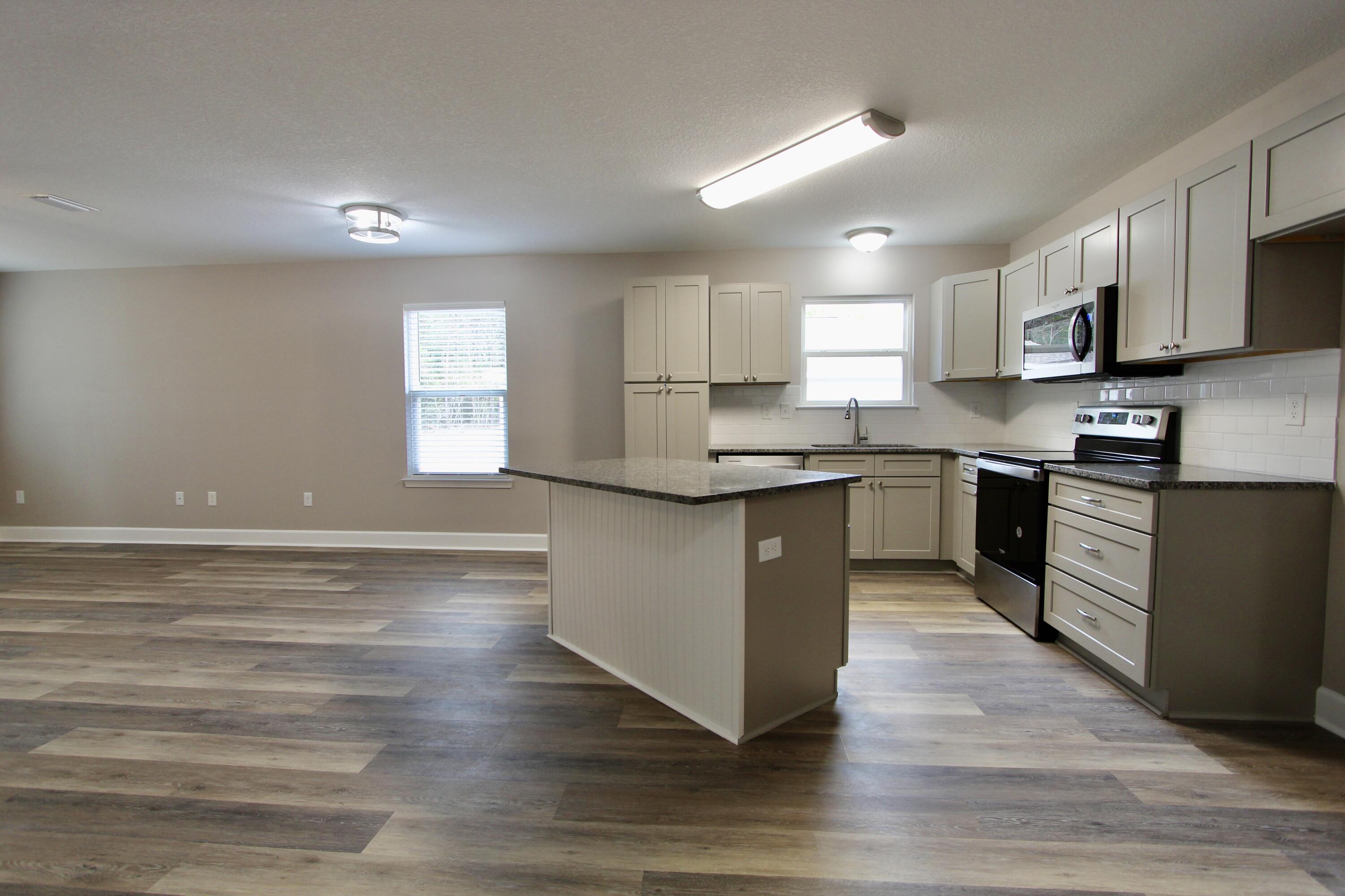 4639 Falcon Way Crestview, FL 32539 - Photo 7 of 40 a kitchen with stainless steel appliances granite countertop a stove top oven a sink dishwasher and white cabinets with wooden floor