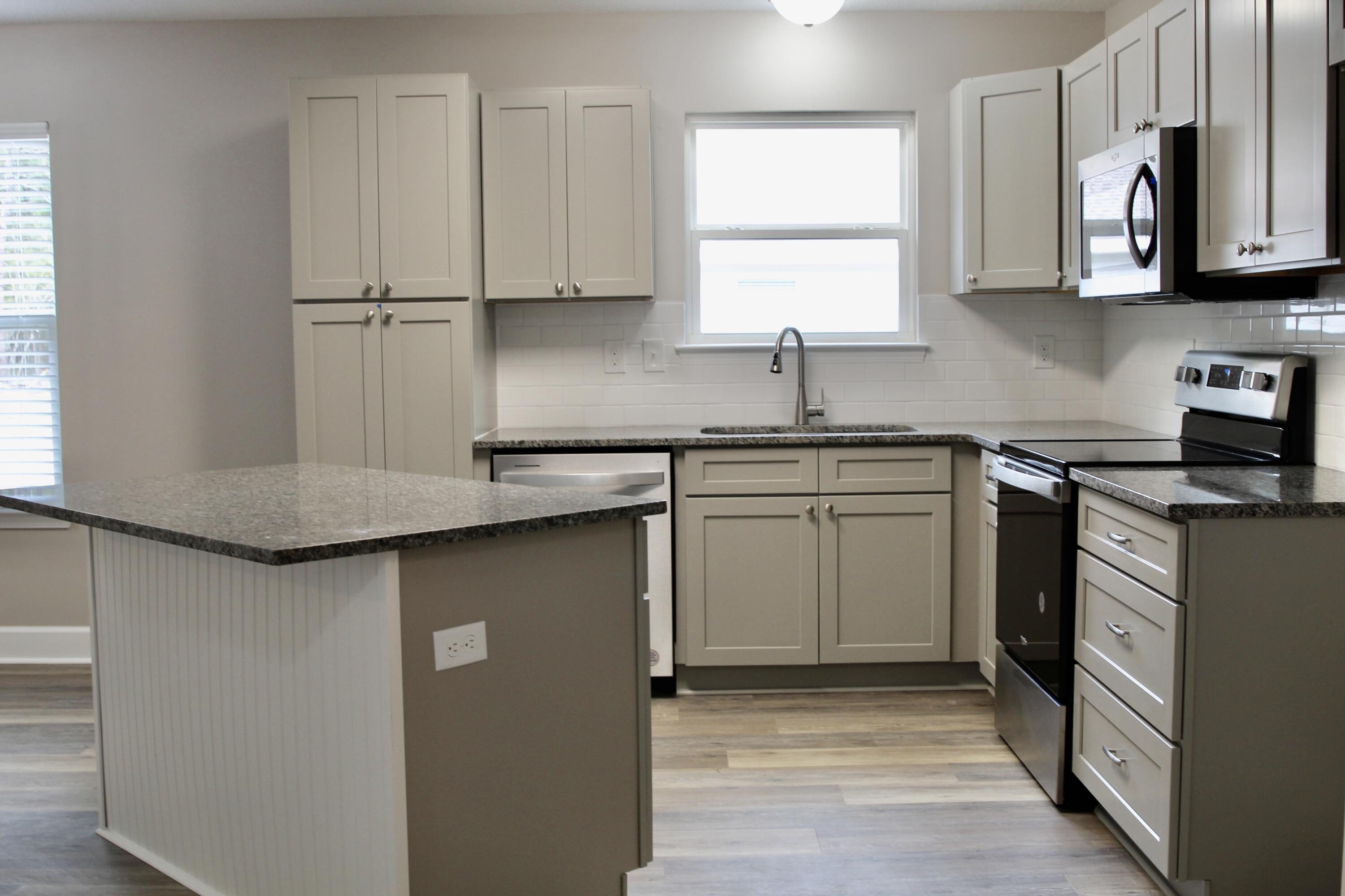4639 Falcon Way Crestview, FL 32539 - Photo 9 of 40 a kitchen with stainless steel appliances granite countertop a sink a stove and dishwasher with wooden cabinets