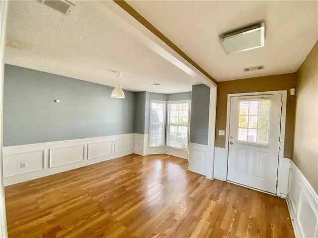 a view of an empty room with window and wooden floor