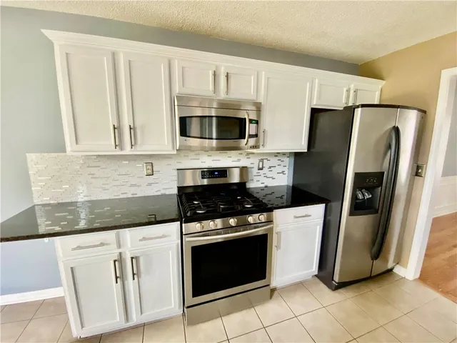 a kitchen with granite countertop a stove sink and refrigerator