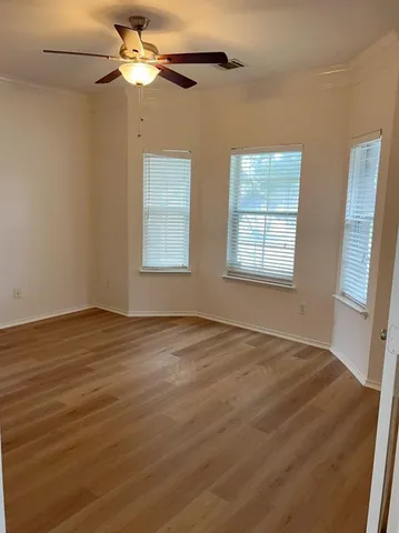 a view of an empty room with a window and wooden floor