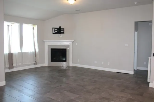 an empty room with windows and fireplace
