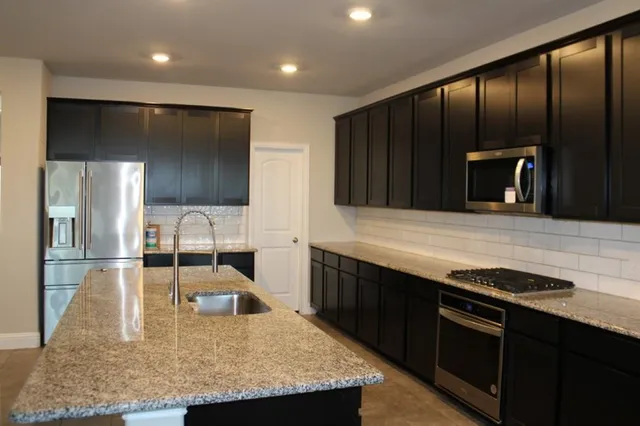 a kitchen with kitchen island granite countertop counter space a sink and stainless steel appliances