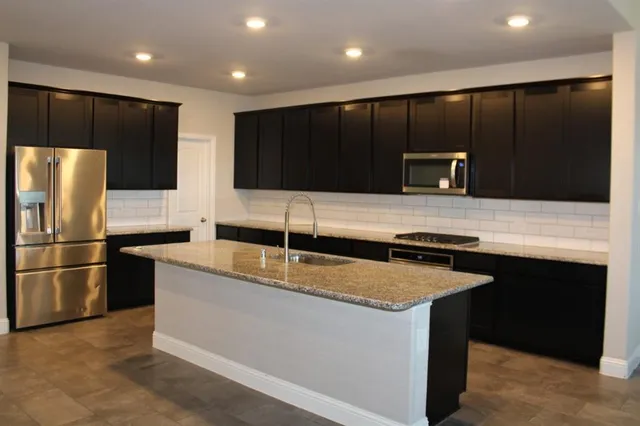 a kitchen with kitchen island stainless steel appliances a sink and a refrigerator