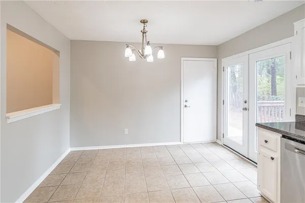 a view of an empty room with window and chandelier fan