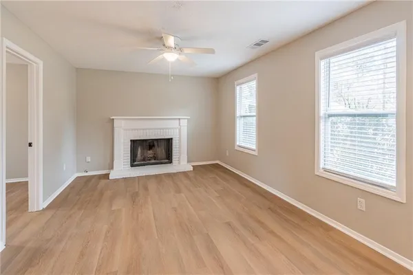 a view of an empty room with wooden floor fireplace and a window