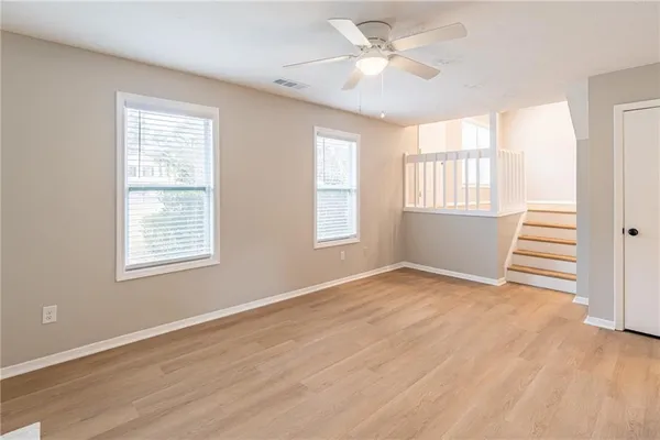a view of an empty room with a window and wooden floor