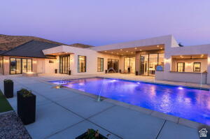 1141 East Lost Ridge Drive Washington, UT 84780 - Photo 11 of 108 Exterior showcasing a rectangular swimming pool with integrated lighting, a spacious concrete patio, and a modern architectural design with large windows and glass doors