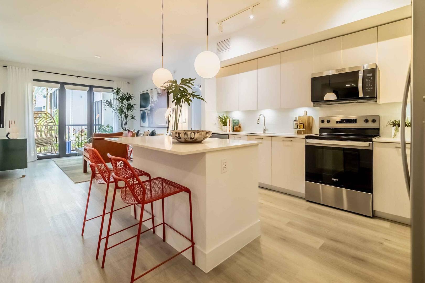 2985 Southwest 122nd Avenue, Unit 101 Miramar, FL 33025 - Photo 4 of 16 a kitchen with stainless steel appliances granite countertop a stove top oven a sink dishwasher a dining table and chairs with wooden floor