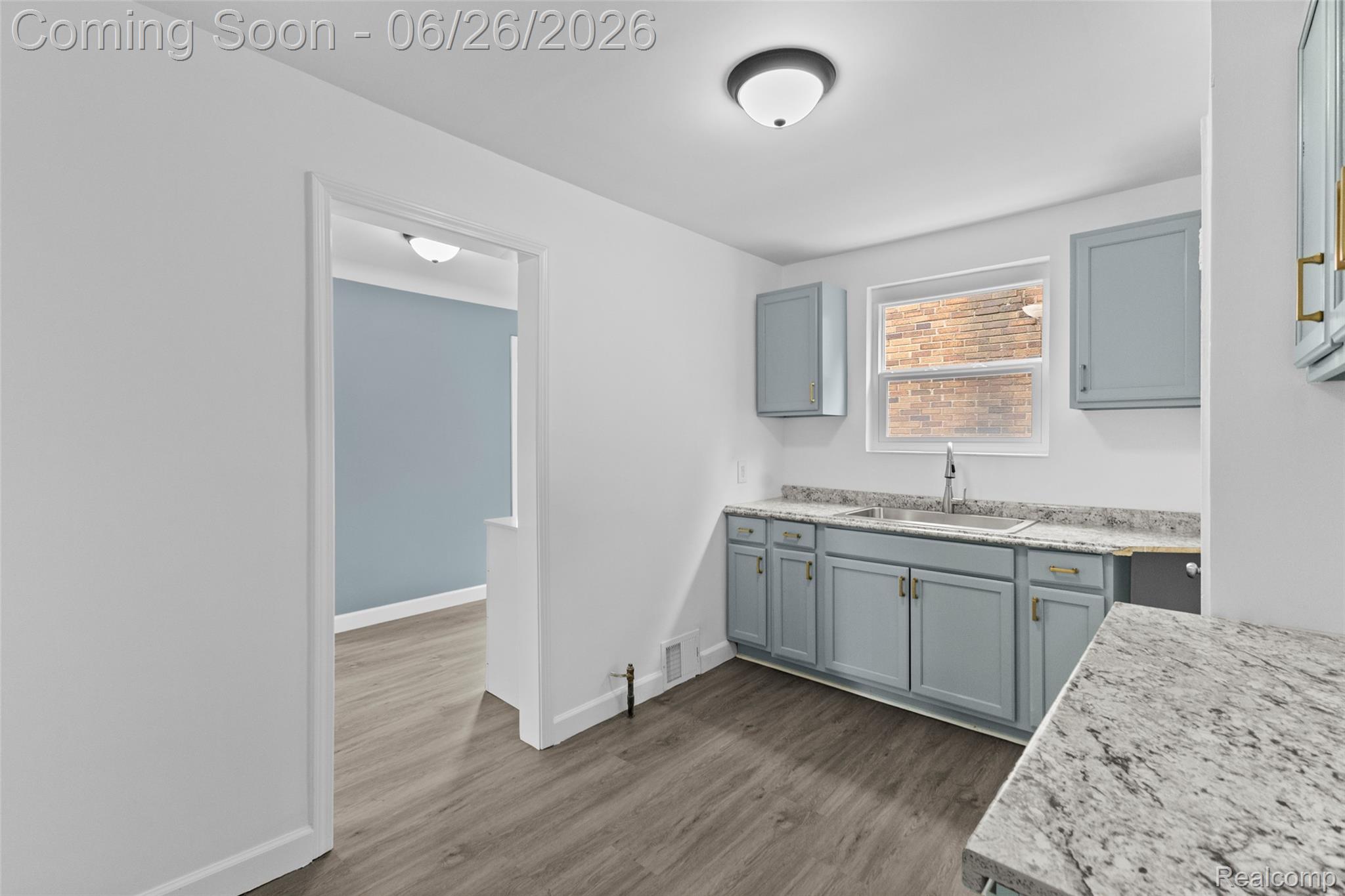 8310 Whitcomb Detroit, MI 48228 - Photo 14 of 26 Kitchen featuring blue-gray cabinetry, granite-style countertops, stainless steel sink with gooseneck faucet, window, and wood-finish flooring