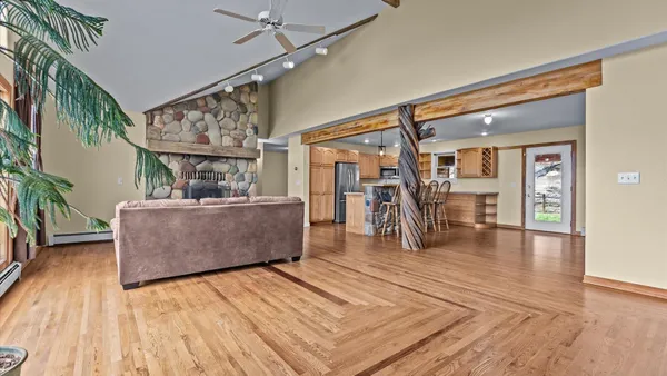a kitchen with stainless steel appliances kitchen island granite countertop a refrigerator a stove top oven a sink dishwasher a dining table and chairs with wooden floor