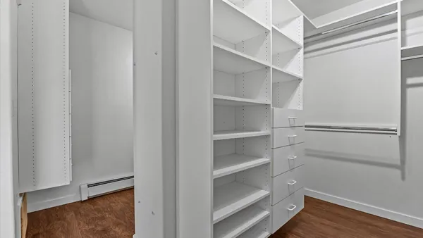 an empty room with wooden floor chandelier fan and windows