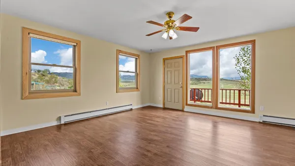 a view of an empty room with a window and wooden floor