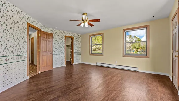 an empty room with wooden floor and windows