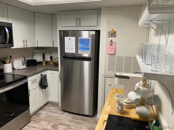 a kitchen with stainless steel appliances granite countertop a refrigerator a stove and a sink with wooden floor