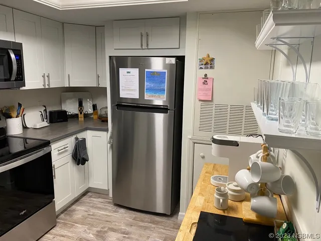 a kitchen with stainless steel appliances granite countertop a refrigerator a stove and a sink with wooden floor