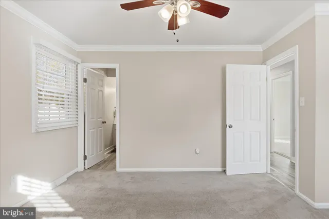 a view of an empty room with chandelier fan