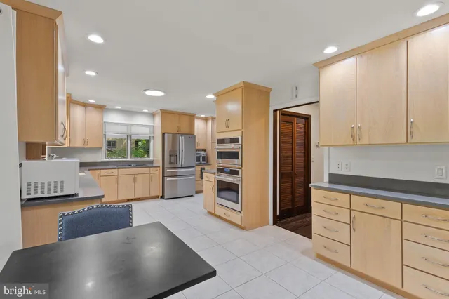 a kitchen with stainless steel appliances kitchen island granite countertop a refrigerator and a stove top oven
