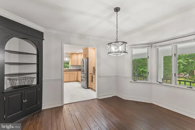 a view of a room with wooden floor chandeliers and kitchen view