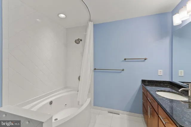 a bathroom with a granite countertop sink and a bathtub