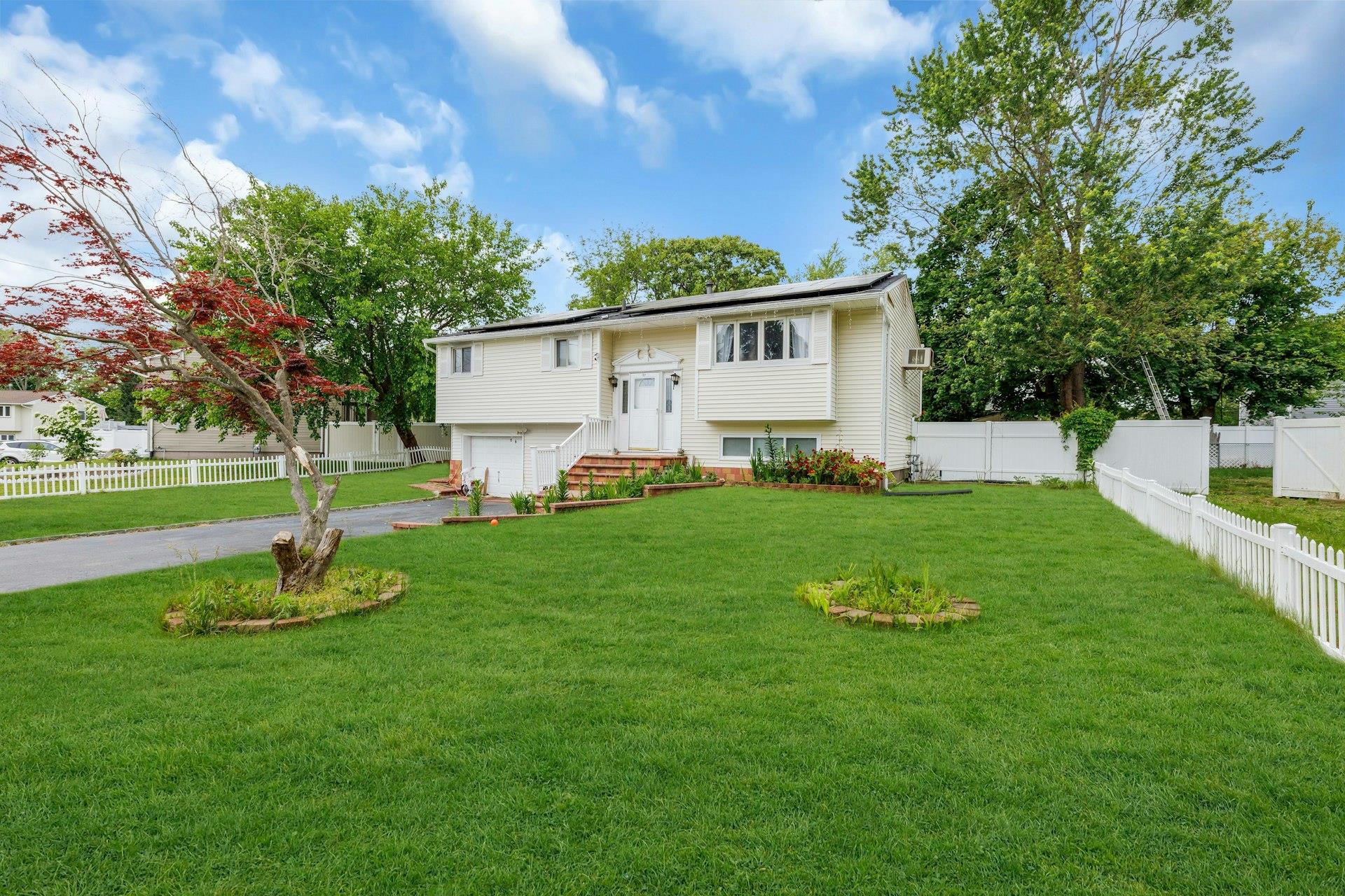 Split foyer home featuring an attached garage, driveway, and roof mounted solar panels
