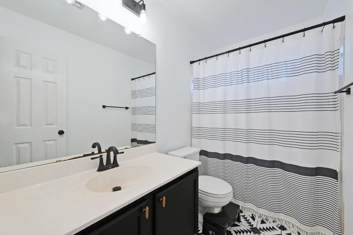 1451 Roxanne's Run Pflugerville, TX 78660 - Photo 15 of 17 a bathroom with a sink a toilet and shower curtain
