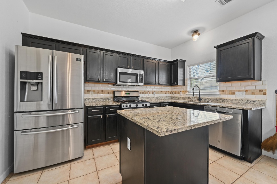 1451 Roxanne's Run Pflugerville, TX 78660 - Photo 6 of 17 a kitchen with kitchen island granite countertop stainless steel appliances and counter space