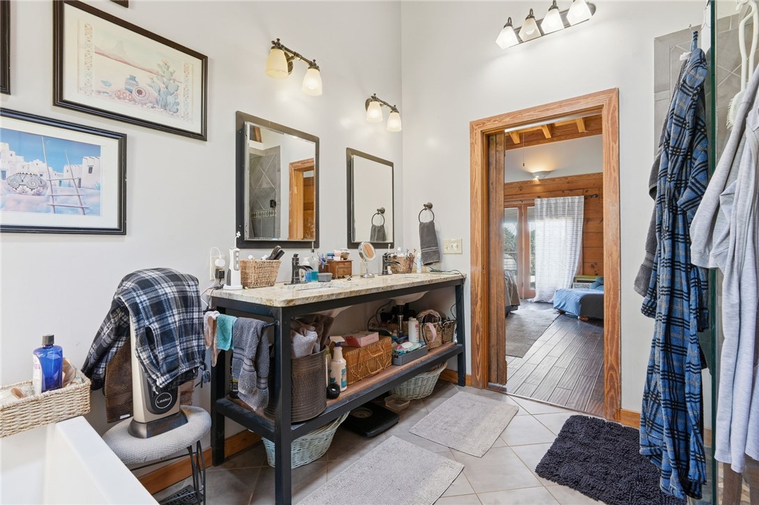 608 Five Forks Road Anderson, SC 29621 - Photo 37 of 43 This bathroom features a double vanity and tile flooring, connecting to an adjoining room with wood flooring.