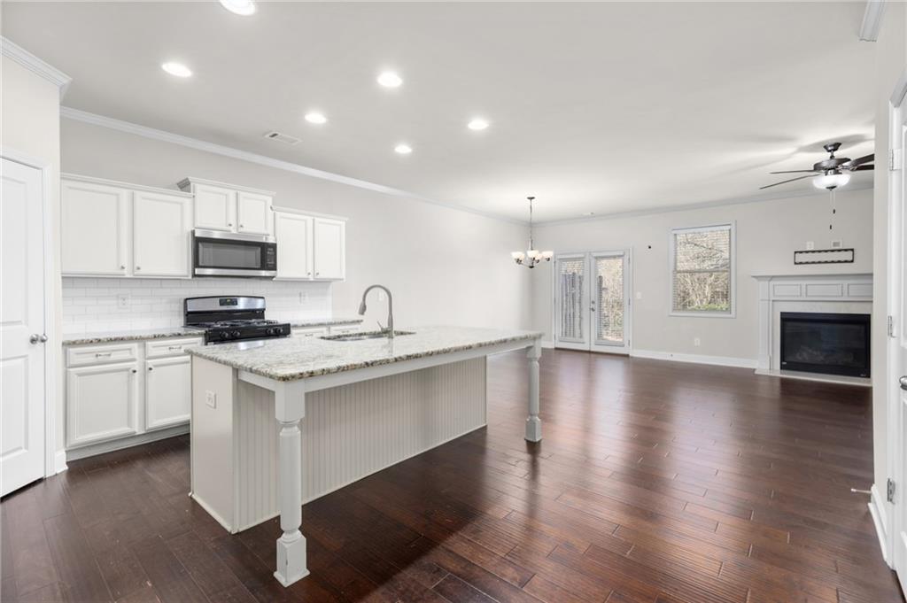 1925 Wheylon Drive Lawrenceville, GA 30044 - Photo 6 of 55 a kitchen with granite countertop a stove top oven a sink dishwasher and a refrigerator with wooden floor