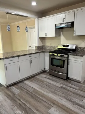 a kitchen with stainless steel appliances granite countertop a stove a sink and white cabinets