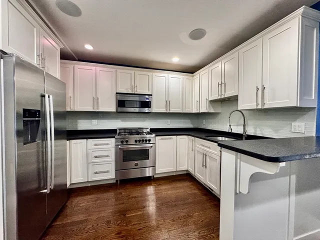 a kitchen with stainless steel appliances granite countertop a stove a sink and a refrigerator