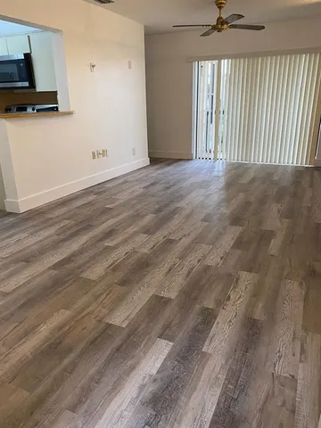 an empty room with wooden floor mirror and windows