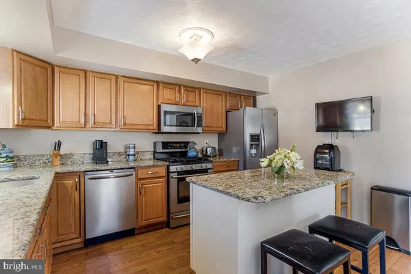 a kitchen with stainless steel appliances granite countertop a stove top oven a sink dishwasher a dining table and chairs with wooden floor