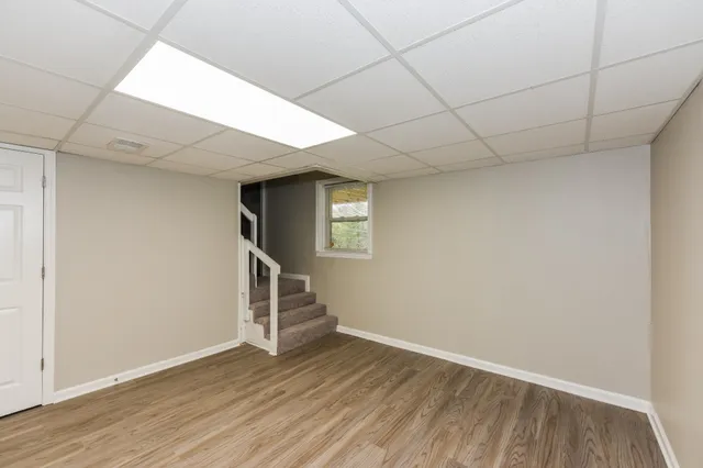 a view of an empty room with wooden floor and stairs