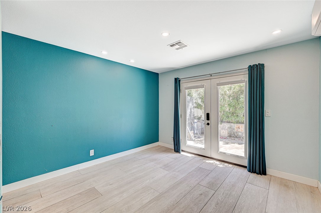 4153 Woodcrest Road Las Vegas, NV 89121 - Photo 32 of 58 French doors open to a serene outdoor space, complementing the room's recessed lighting and modern flooring.