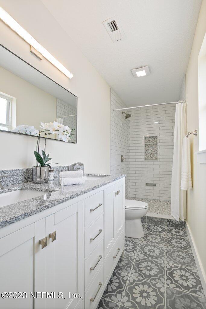 2746 Sam Road Jacksonville, FL 32216 - Photo 32 of 44 a bathroom with a granite countertop sink mirror vanity and toilet