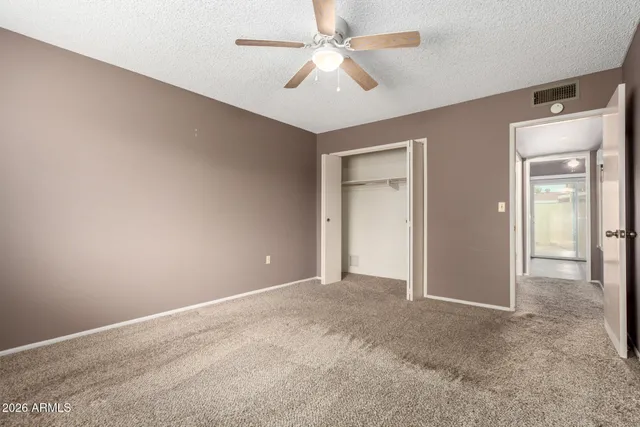 an empty room with windows and ceiling fan
