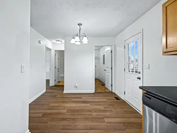 a view of a hallway with wooden floor and chandelier