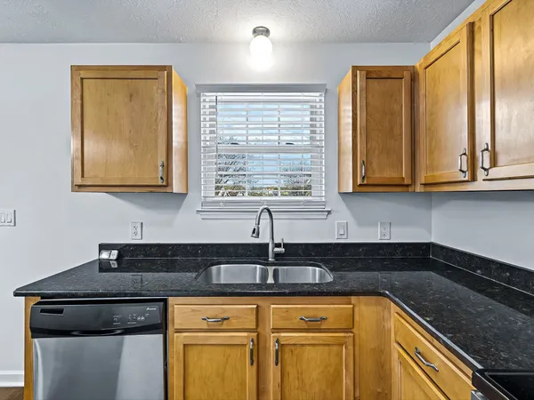 a kitchen with granite countertop a sink a stove and cabinets