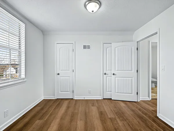 an empty room with wooden floor and windows