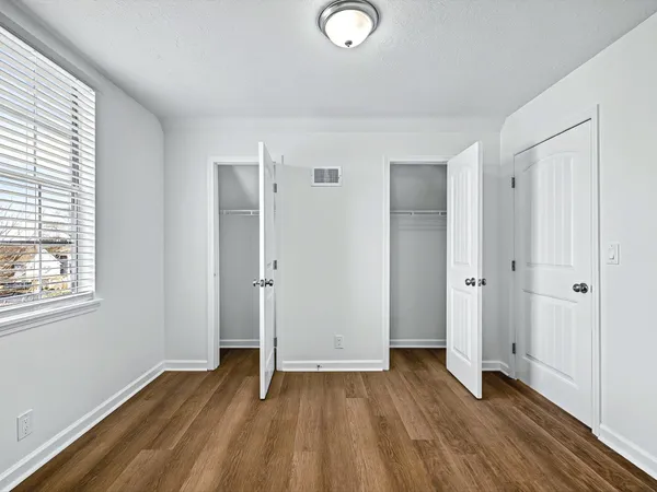 an empty room with wooden floor and windows