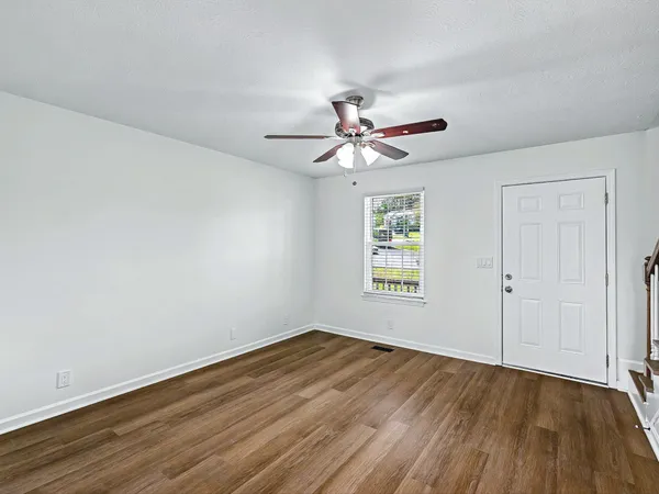 an empty room with wooden floor and windows