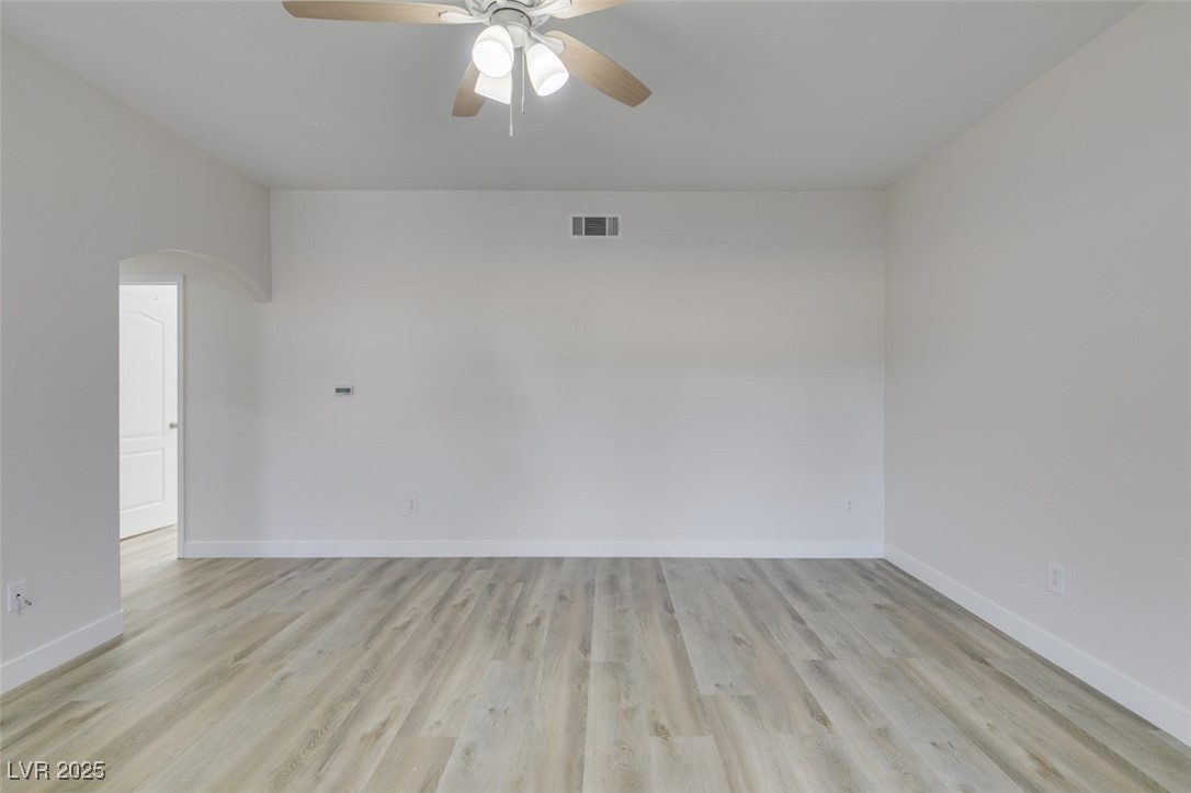5525 West Flamingo Road, Unit 1028 Las Vegas, NV 89103 - Photo 15 of 42 Empty room with light wood-style flooring, ceiling fan, and arched walkways