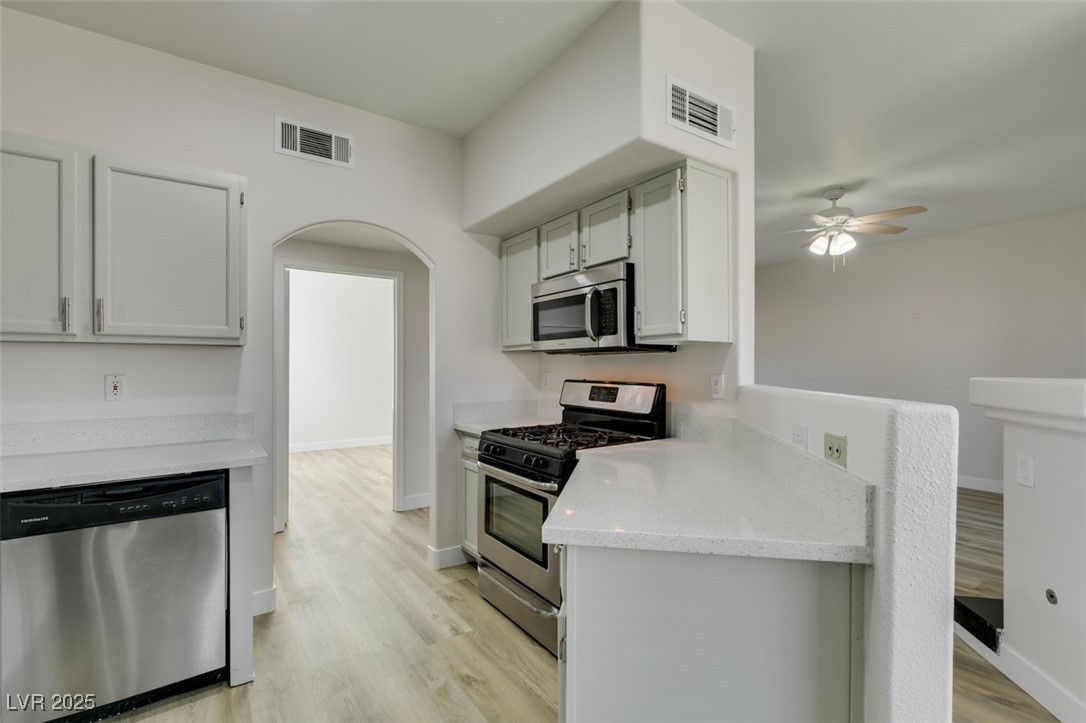 5525 West Flamingo Road, Unit 1028 Las Vegas, NV 89103 - Photo 29 of 42 Kitchen with appliances with stainless steel finishes, light wood-style floors, arched walkways, and light stone countertops