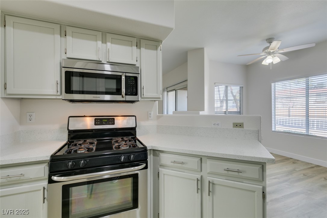 5525 West Flamingo Road, Unit 1028 Las Vegas, NV 89103 - Photo 33 of 42 Kitchen featuring stainless steel appliances, white cabinets, light stone countertops, light wood-style floors, and a peninsula