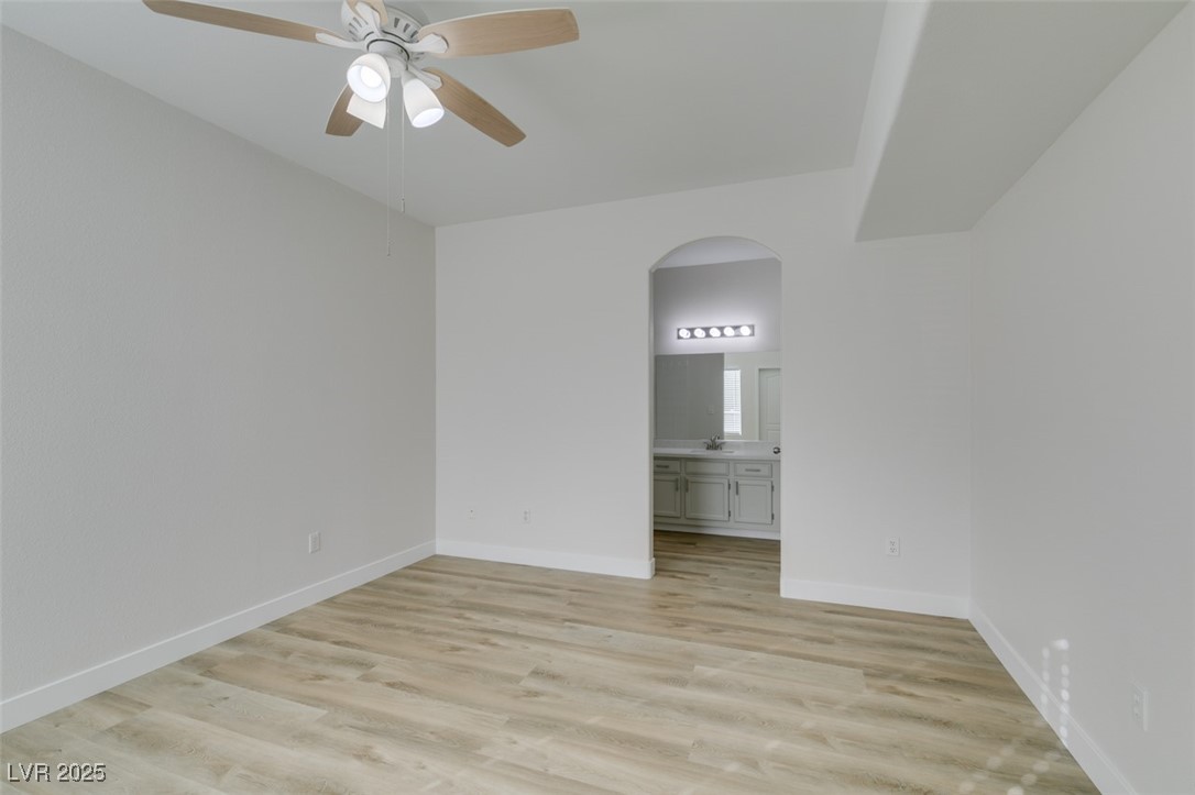5525 West Flamingo Road, Unit 1028 Las Vegas, NV 89103 - Photo 36 of 42 Unfurnished bedroom with arched walkways, light wood-type flooring, a ceiling fan, and connected bathroom